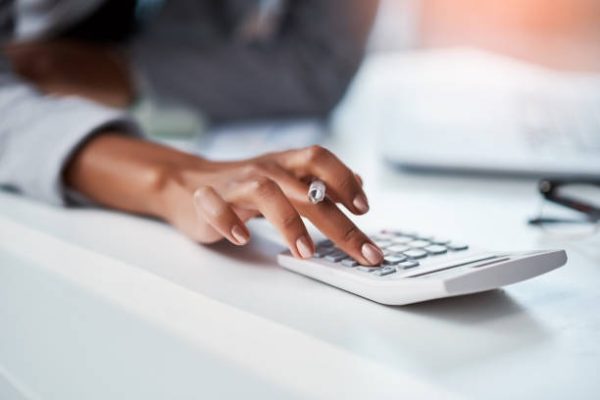 Cropped shot of a businesswoman using a calculator at her desk in a modern office
