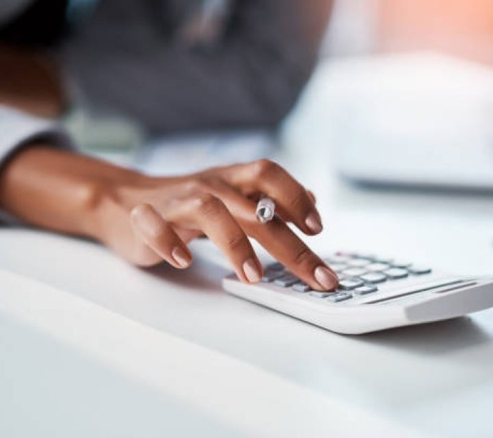 Cropped shot of a businesswoman using a calculator at her desk in a modern office